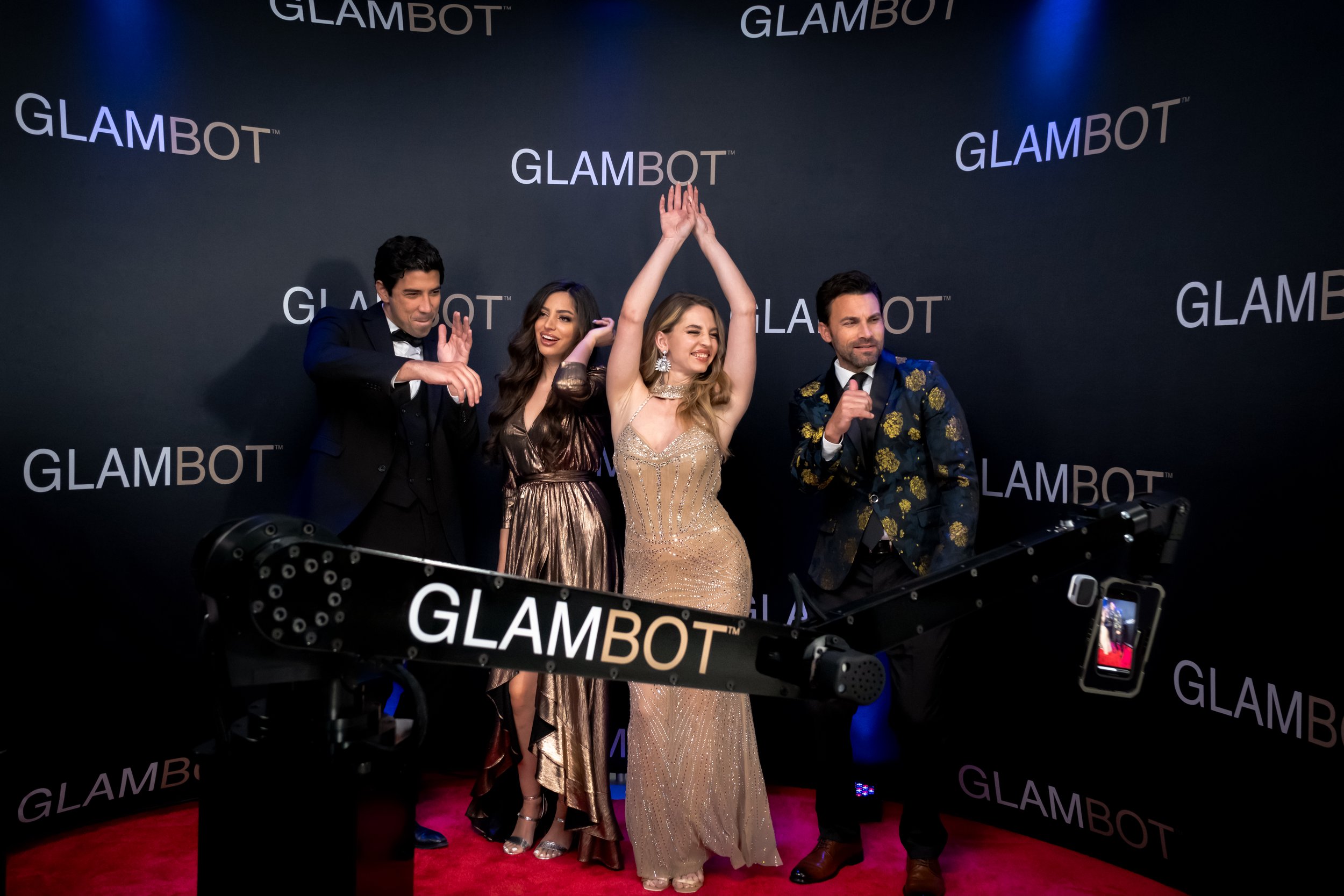 Group of guests cheering on the red carpet in front of GlamBot step-and-repeat