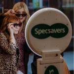 Guests pose wearing sunglasses beside a Specsavers-branded Presto booth