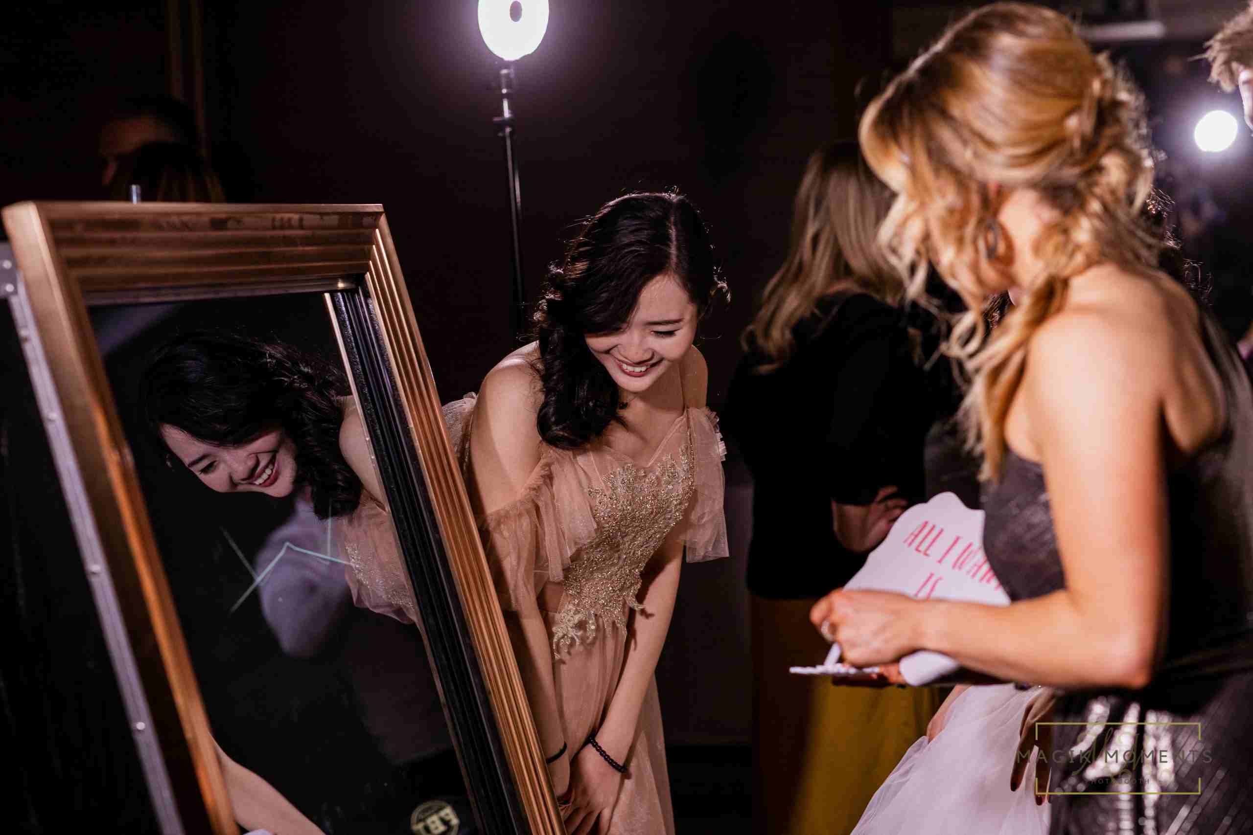 Guest laughing while using Magik Mirror Photo Booth at an event